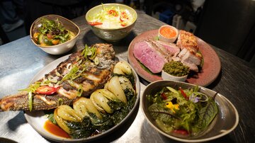 A hearty dish with grilled fish, fresh vegetables, and various side dishes. The presentation displays a variety of colors and ingredients.
