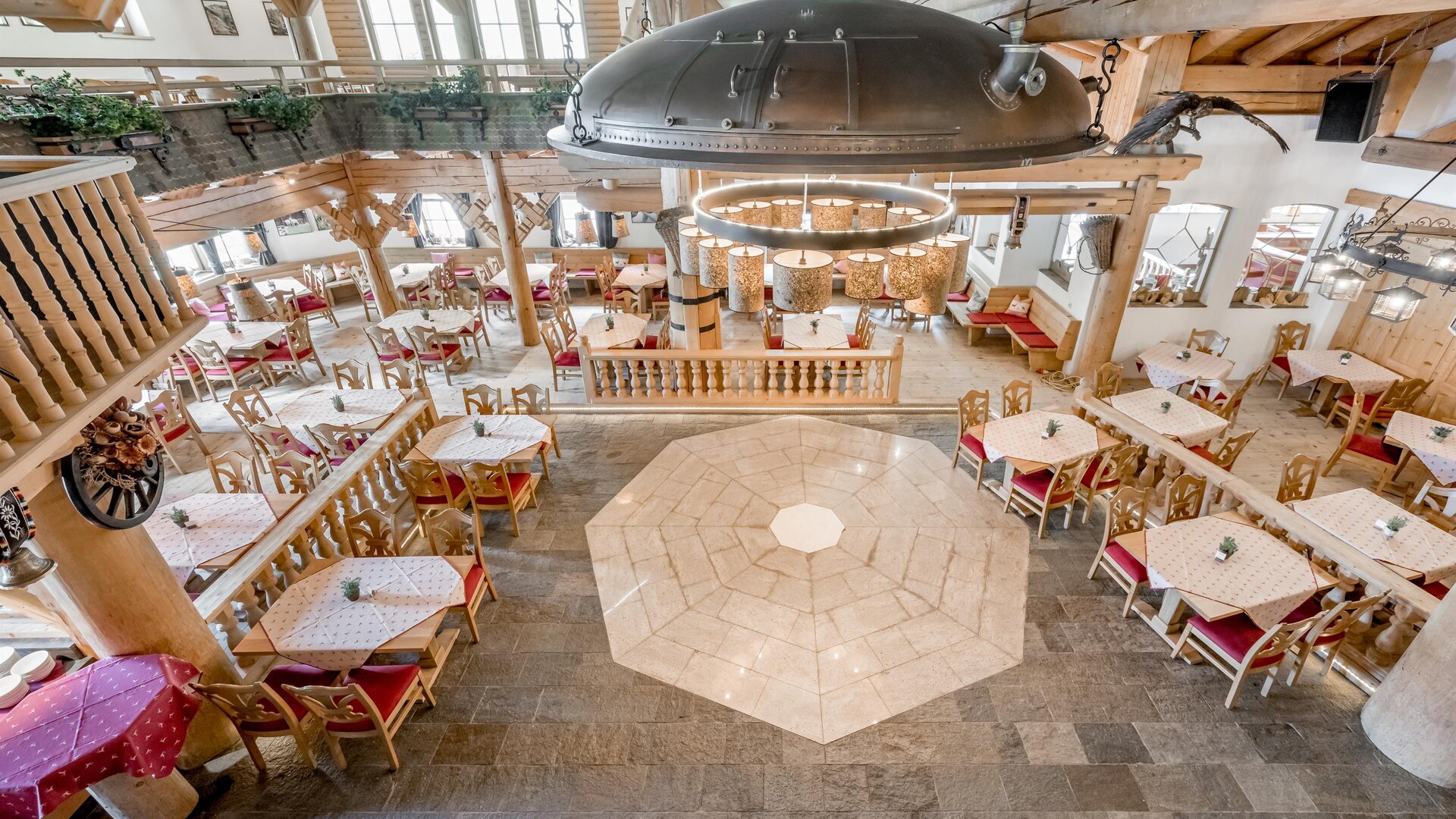 A cozy restaurant with stylish wooden paneling and adjoining dining areas. The tables are lovingly set, and the lighting concept creates an inviting atmosphere.
