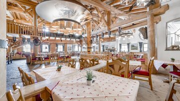 An inviting restaurant with wooden decor and cozy tables. Large windows provide plenty of light and a view of the cozy atmosphere.