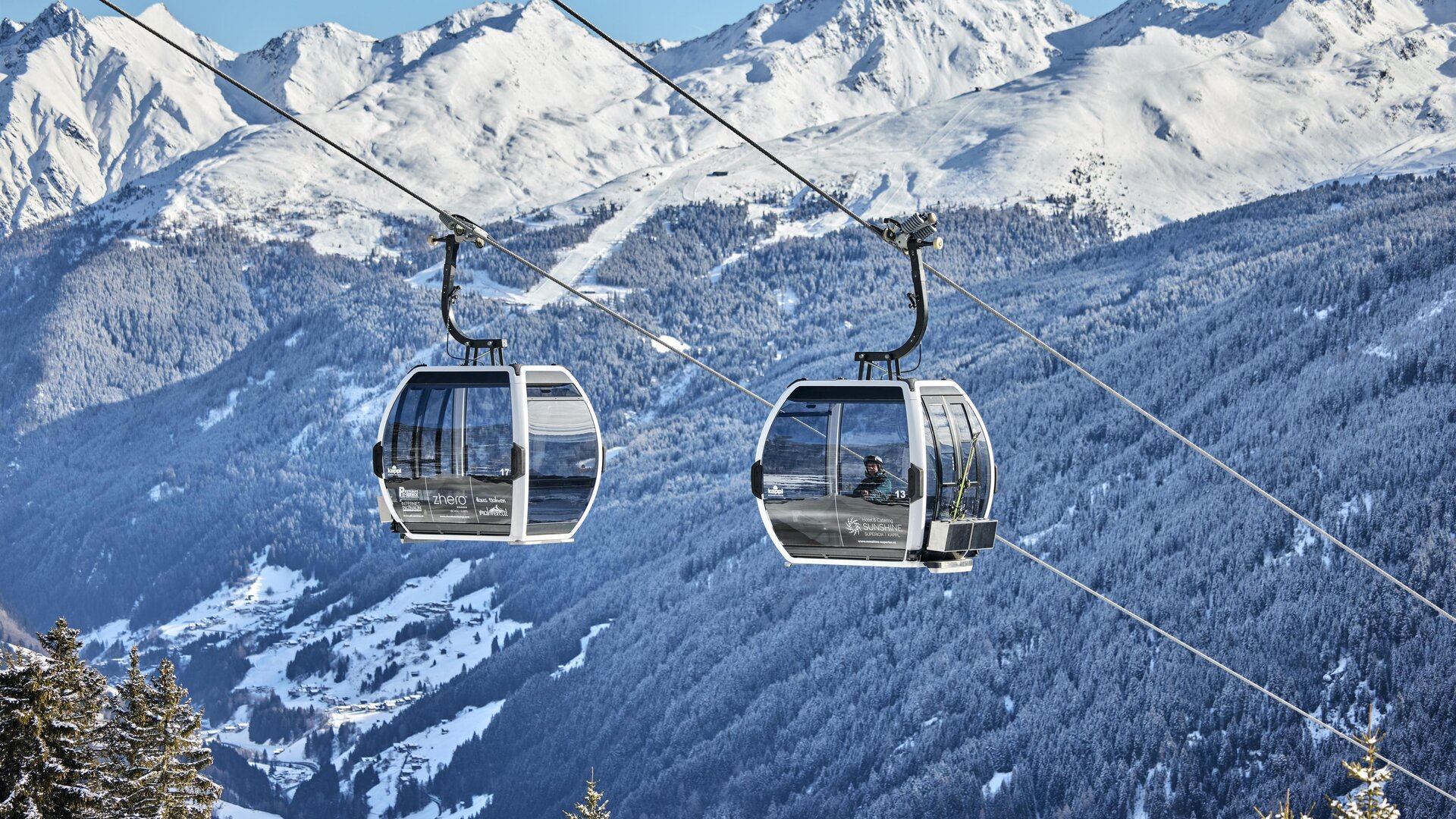 A skier glides over a snow-covered slope in the mountains. In the background, majestic mountains and a clear sky can be seen.