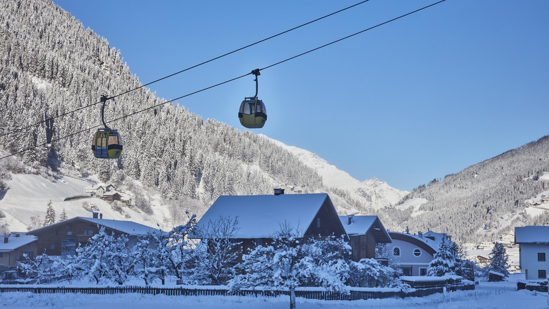 A skier is going down the snow-covered slope. In the background, majestic mountains are visible.