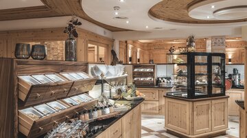 Ein stilvolles Geschäft mit Holzverkleidung und einer Auswahl an Delikatessen. Die Vitrine präsentiert verschiedene Produkte und sorgt für eine einladende Atmosphäre.