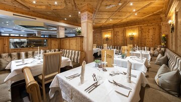 Ein gemütliches Restaurant mit Holzverkleidung und eleganten Tischen. Die Atmosphäre ist einladend und warm.