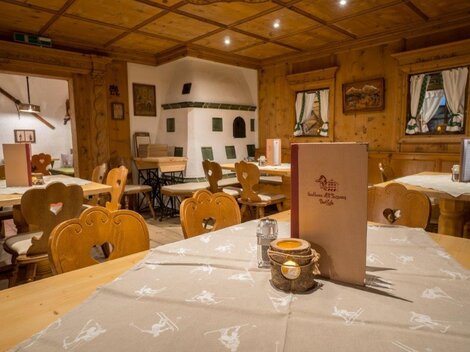 Ein gemütliches Restaurant mit Holzvertäfelung und rustikalen Tischen. Die Tische sind sauber gedeckt und es gibt eine einladende Atmosphäre.