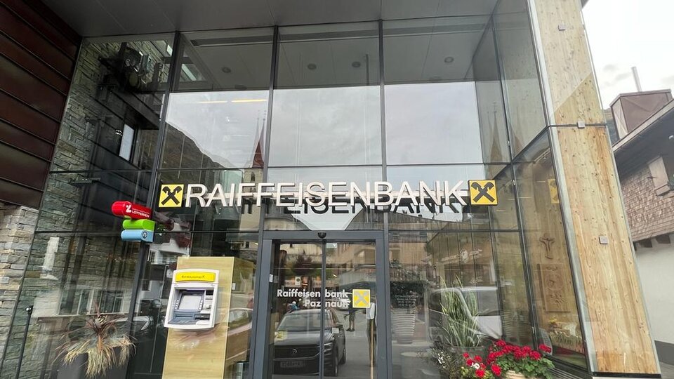 Entrance to the Raiffeisenbank with modern architecture. A cash machine and plants can be seen on the facade.