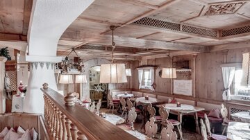 Ein gemütliches Restaurant mit Holzdekor und bequemen Tischen. Warmes Licht schafft eine einladende Atmosphäre.
