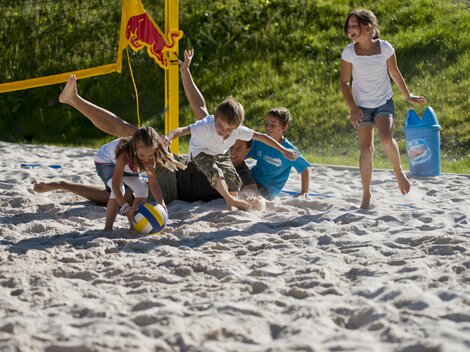 Kinder spielen Volleyball am Strand. Sie haben Spaß im Sand und genießen die Sonne.