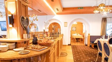 Ein einladendes Restaurant mit warmen Holzelementen und gemütlichen Tischen. Die Theke ist mit leckeren Süßigkeiten dekoriert.