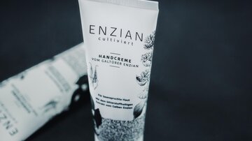 A hand cream in an elegant tube with the print "ENZIAN". The packaging features floral motifs and highlights the caring properties.