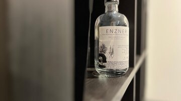 A bottle of ENZNER on a shelf. The bottle is clear and has a simple, elegant design.