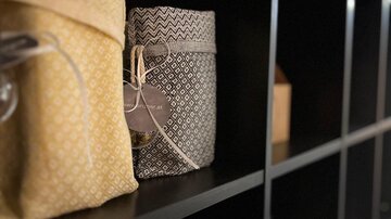 Two decorative bags in yellow and gray are on a shelf. In the background, additional shelf compartments are visible.