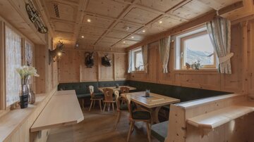 Ein gemütliches, holzverkleidetes Restaurant mit Tischen und Stühlen. Große Fenster sorgen für viel Tageslicht und eine einladende Atmosphäre.