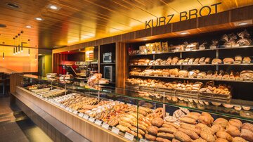 A modern bakery with a wide selection of fresh rolls and breads. The presentation of the baked goods is attractive and inviting.