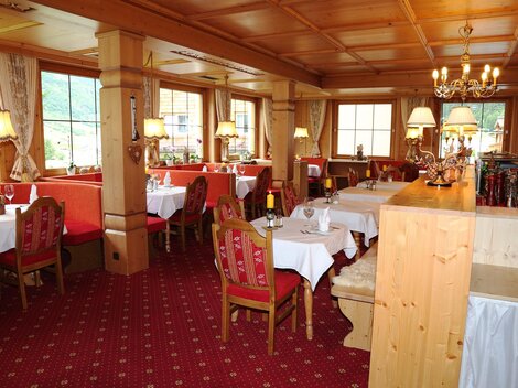 A cozy restaurant with wooden furniture and red seats. Soft lighting creates an inviting atmosphere.