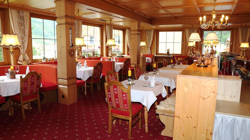 A cozy restaurant with wooden furniture and red seats. Soft lighting creates an inviting atmosphere.