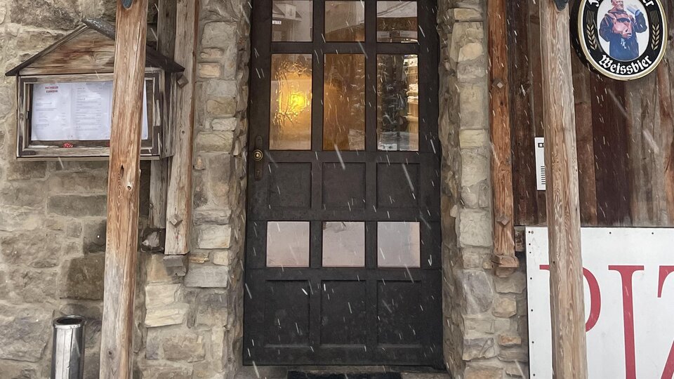 Ein traditionelles Restaurant mit einem holzverzierten Eingang. Schnee bedeckt das Dach und sorgt für eine gemütliche Atmosphäre.