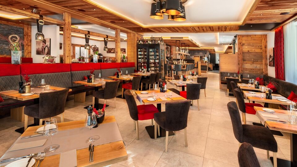 Ein modernes Restaurant mit Holzverkleidung und gemütlicher Sitzgelegenheit. Die Tische sind ordentlich gedeckt und es herrscht eine einladende Atmosphäre.