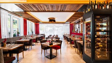 Ein modernes Restaurant mit eleganter Einrichtung und warmem Holzdekor. Die Tische sind liebevoll gedeckt und laden zum Verweilen ein.