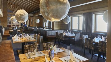 Ein stilvolles Restaurant mit Holzwänden und eleganten Tischen. Die auffälligen, runden Lampen verleihen der Atmosphäre einen modernen Touch.