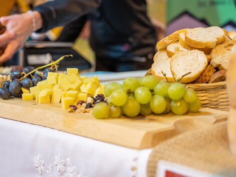 A beautifully laid table with fresh bread, cheese, grapes, and nuts. The colorful presentation invites you to enjoy.