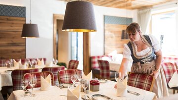 Ein gemütliches Restaurant mit einem einladenden Ambiente. Eine Kellnerin deckt den Tisch mit eleganten Gläsern und Servietten.