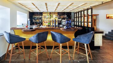 Eine elegante Bar mit modernen Barstühlen und einer gut sortierten Getränkeauswahl. Die Beleuchtung schafft eine einladende Atmosphäre.