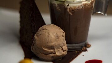 Ein elegantes Dessert mit einer Schokoladentasse, Sahnehaube und frischer Minze. Daneben liegt ein Schokoladeneis und ein Stück Kuchen auf einem kunstvoll dekorierten Teller.