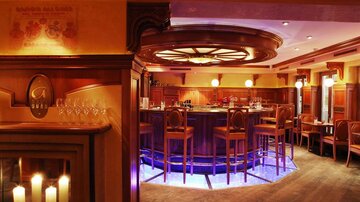 Eine elegante Bar mit Holzdekor und stilvollen Sitzplätzen. Sanftes Licht und dezente Farben schaffen eine gemütliche Atmosphäre.