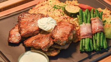 A delicious meat dish with tender steak, a side of potatoes and vegetables. It is accompanied by fresh green beans and a tasty sauce.