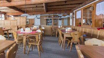 Ein gemütliches Restaurant mit Holzmöbeln und einer warmen Atmosphäre. Es gibt mehrere Tische und eine einladende Einrichtung.