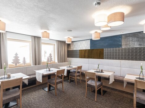 A modern restaurant with bright walls and stylish lamps. There are simple wooden tables and cozy chairs that create an inviting atmosphere.