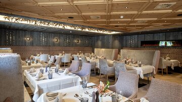 Ein elegantes Restaurant mit stilvollen Tischen und gemütlichen Sitzplätzen. Die wunderschöne Holzdecke und die dekorative Beleuchtung schaffen eine einladende Atmosphäre.
