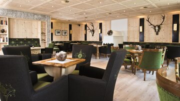 Ein modernes Restaurant mit hellem Holzdekor. Die Einrichtung umfasst elegante Stühle und Tischgruppen in einem gemütlichen Ambiente.