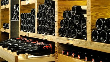 Ein Regalsystem mit vielen Weinflaschen in dunklen und hellen Holzkisten. Die Flaschen sind ordentlich gestapelt und warten auf den Verkauf.