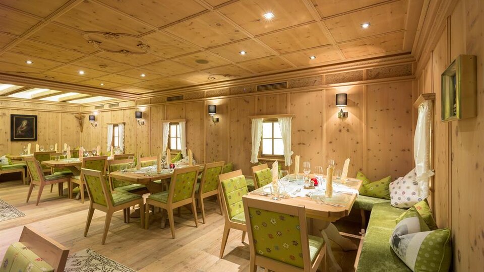 Ein gemütlicher Raum mit Holzwänden und eleganter Einrichtung. Mehrere Tische und Stühle sind bereit für Gäste.