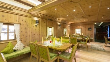 Ein gemütliches Restaurant mit Holzdekor und grünen Akzenten. Die Tische sind für Gäste dekoriert und laden zum Verweilen ein.