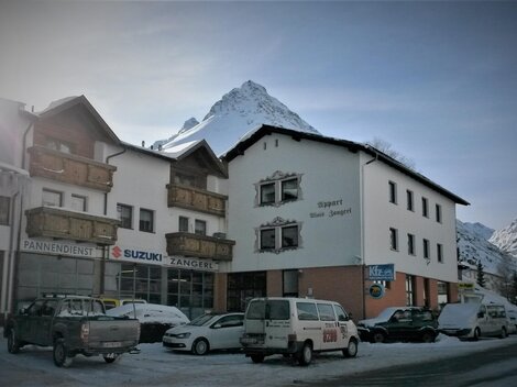 A charming building in the mountains, surrounded by snow. In the background, a majestic peak can be seen.