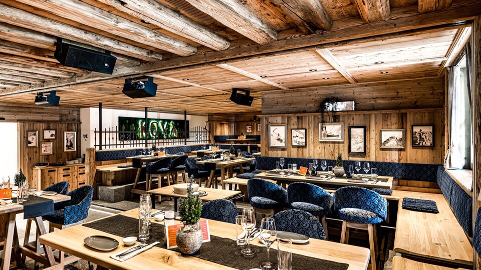 Ein modernes Restaurant mit Holzinterieur und gemütlicher Atmosphäre. Die Tische sind elegant gedeckt und bieten Platz für viele Gäste.