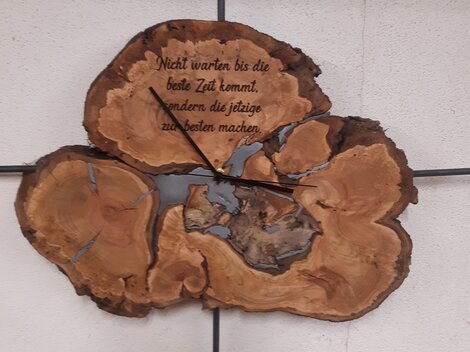 A decorative wall clock made of wood with a unique shape. It features the saying: "Do not wait for the best time to come, but make use of the present."
