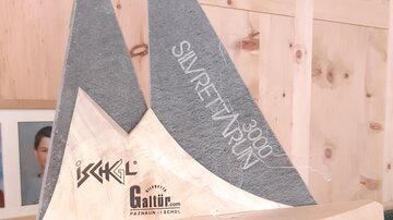 Eine dekorative Holzskulptur in Form eines Segelboots mit grauen und hellen Elementen. Die Skulptur trägt die Inschrift "Silvretta Run", was auf ein Event oder eine Auszeichnung hindeutet.
