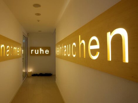 A bright hallway with stylish wooden signs. The words “breathe,” “calm,” and “exhale” gently glow, conveying a soothing atmosphere.