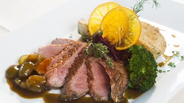 Ein leckeres Gericht mit zartem Fleisch, Brokkoli, und einer Orangenscheibe. Dazu gibt es eine feine Sauce und verschiedene Beilagen.