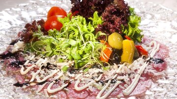 Ein ansprechend angerichtetes Carpaccio mit frischem Gemüse, Salat und speziellen Saucen. Die Präsentation ist farbenfroh und einladend.