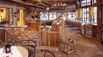 Ein gemütliches Restaurant im Holzstil mit rustikalen Möbeln und warmem Licht. Große Fenster bieten einen Blick nach draußen und schaffen eine einladende Atmosphäre.