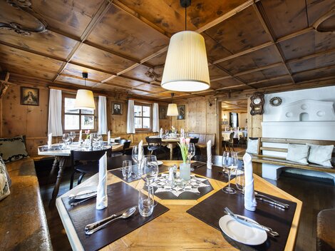 A cozy restaurant with wooden paneling and elegant tables. The warm lighting creates an inviting atmosphere.