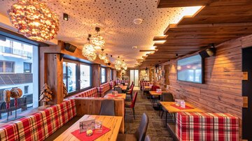 Ein gemütliches Restaurant mit Holzdekor und rustikalen Tischen. Die Wände sind mit Fenstern ausgestattet, die viel Licht hereinlassen.