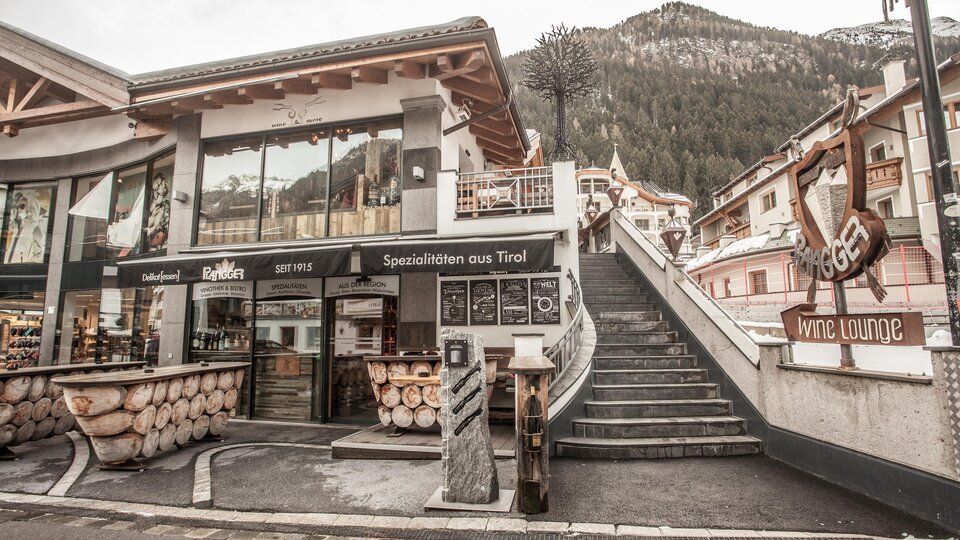 Ein gemütlicher Ort mit Holzmöbeln und einem einladenden Restaurant. Im Hintergrund sind die Berge sichtbar, was eine alpine Atmosphäre schafft.