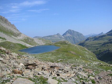A picturesque mountain landscape with a clear blue lake. In the background, majestic mountains rise under a blue sky.