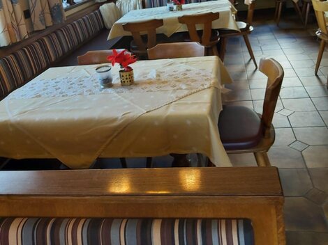 An inviting restaurant with nicely set tables and wooden benches. The atmosphere is cozy and friendly.