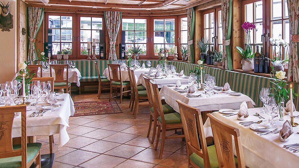 Ein elegantes Restaurant mit Holzmöbeln und gemütlicher Atmosphäre. Die Tische sind festlich mit Gläsern und Blumen dekoriert.